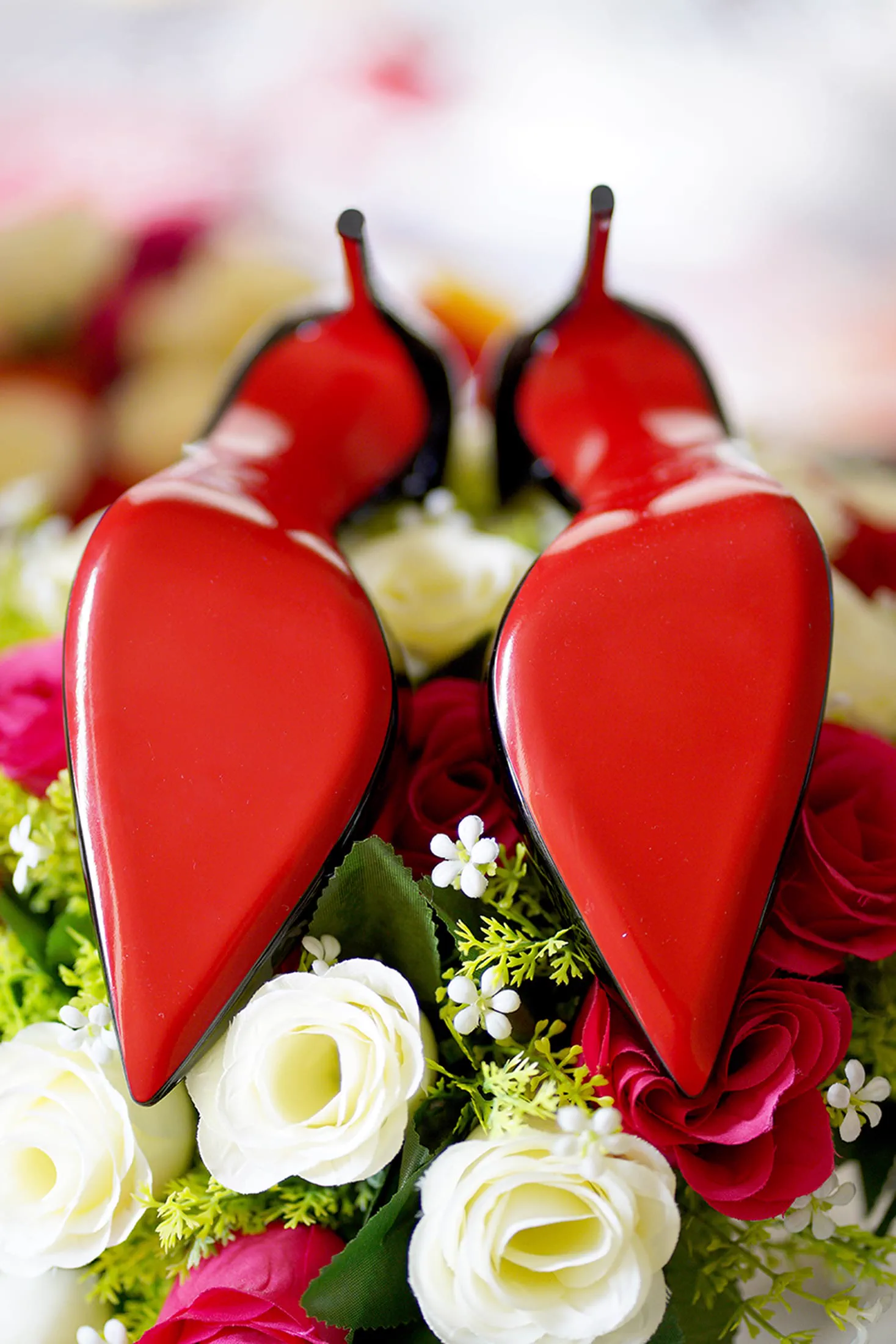 Red-soled heels rest among red and ivory flowers in a Sweet 16 detail portrait.
