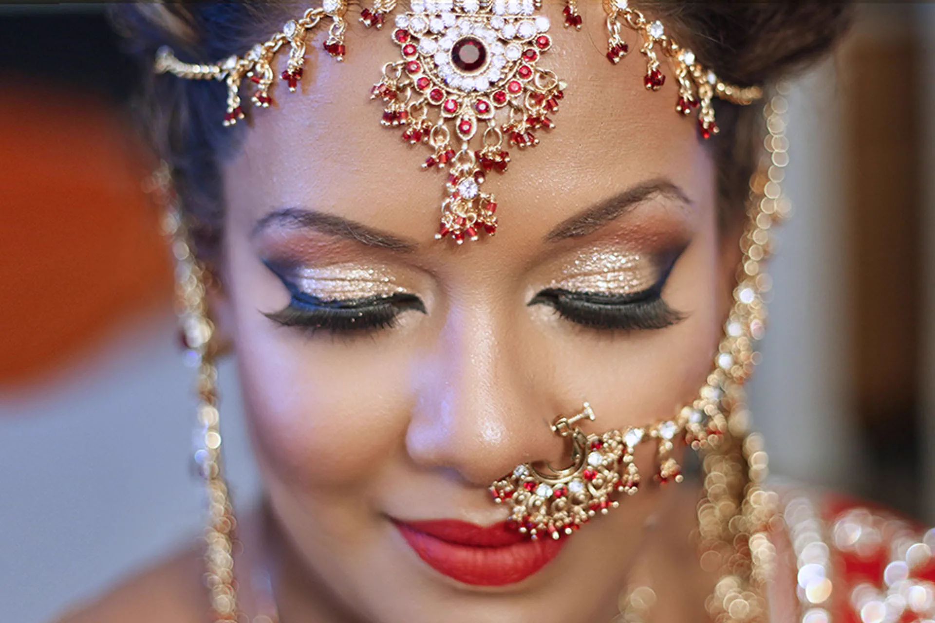 A macro beauty portrait of a bride's eye makeup, nose ring, and maang tikka.