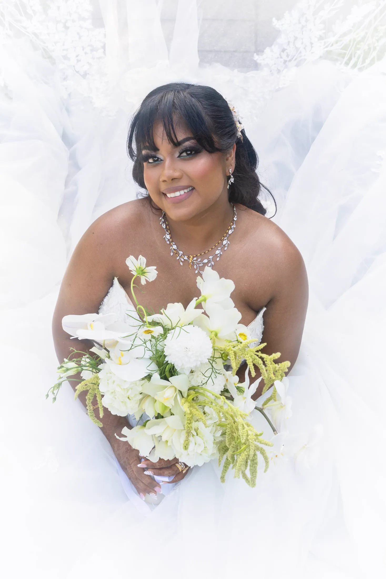 A bride in her veil holds her bouquet in a close bridal portrait.