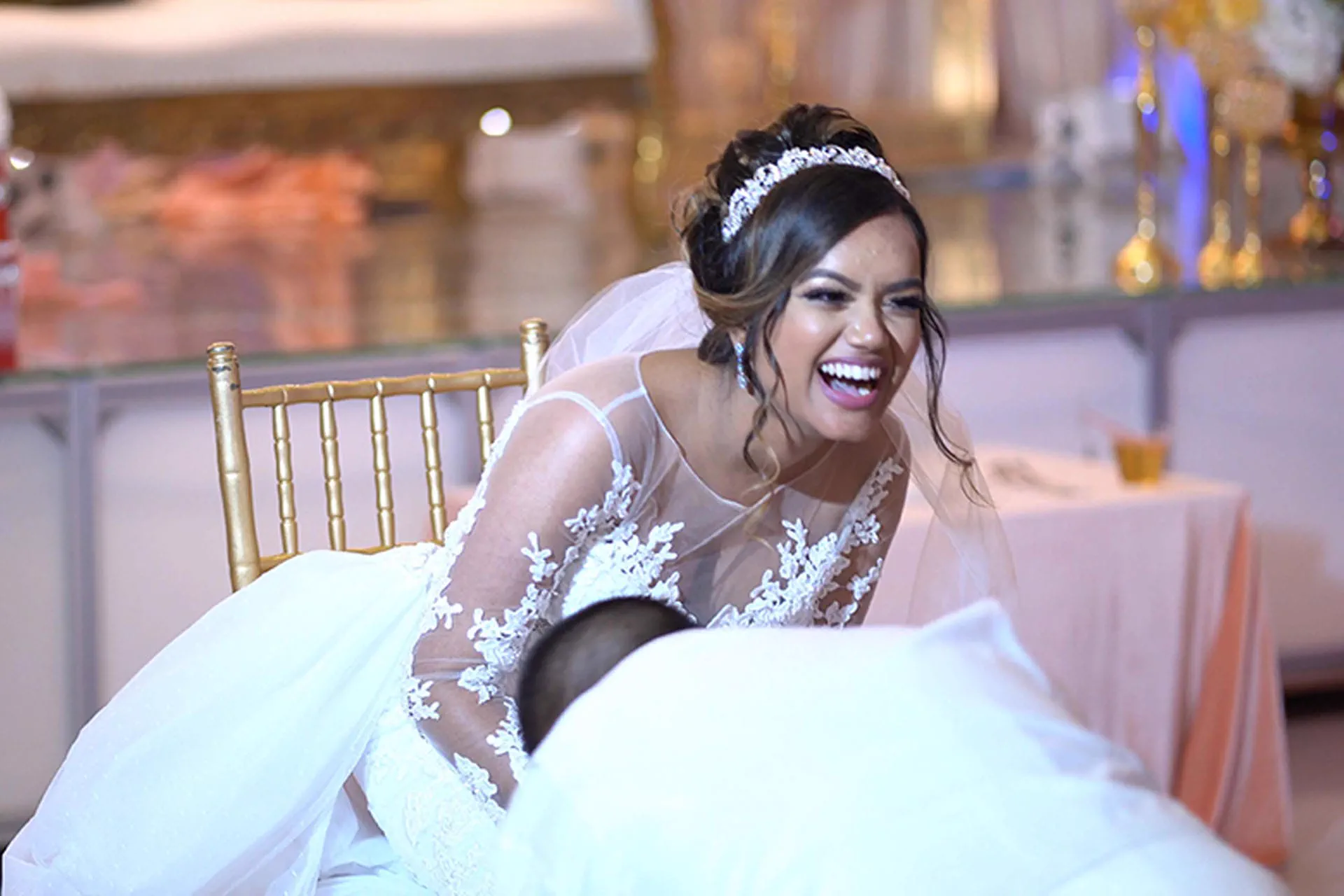 A bride laughs candidly while leaning across the reception table.