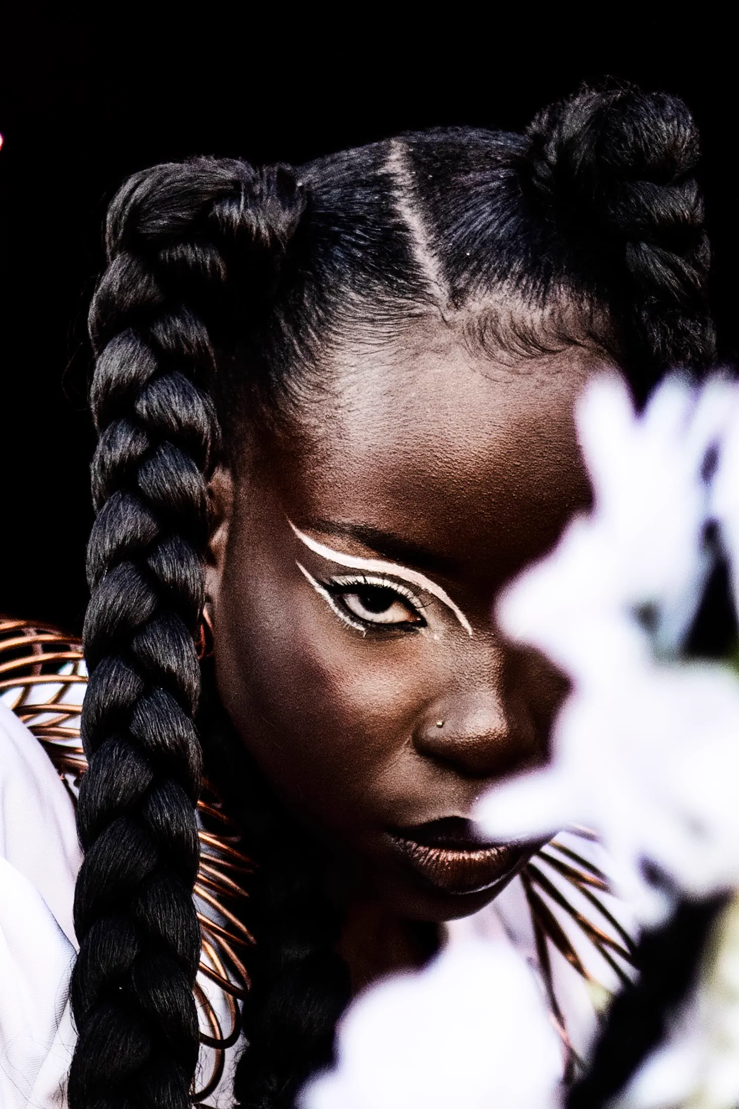 A close avant-garde beauty portrait with sculptural braided hair and graphic eye makeup.