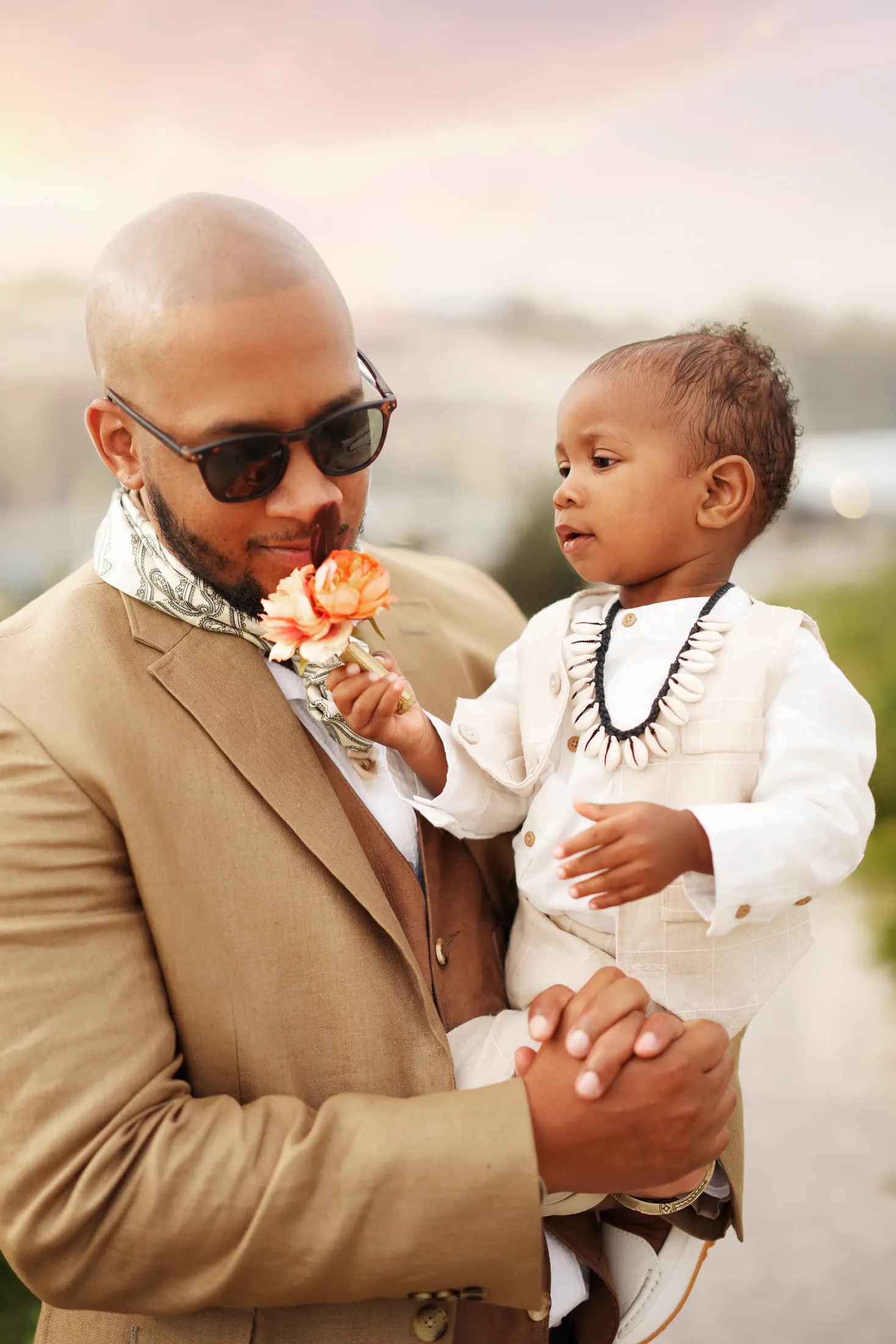 A father in a tan suit shares a tender moment with his young son.