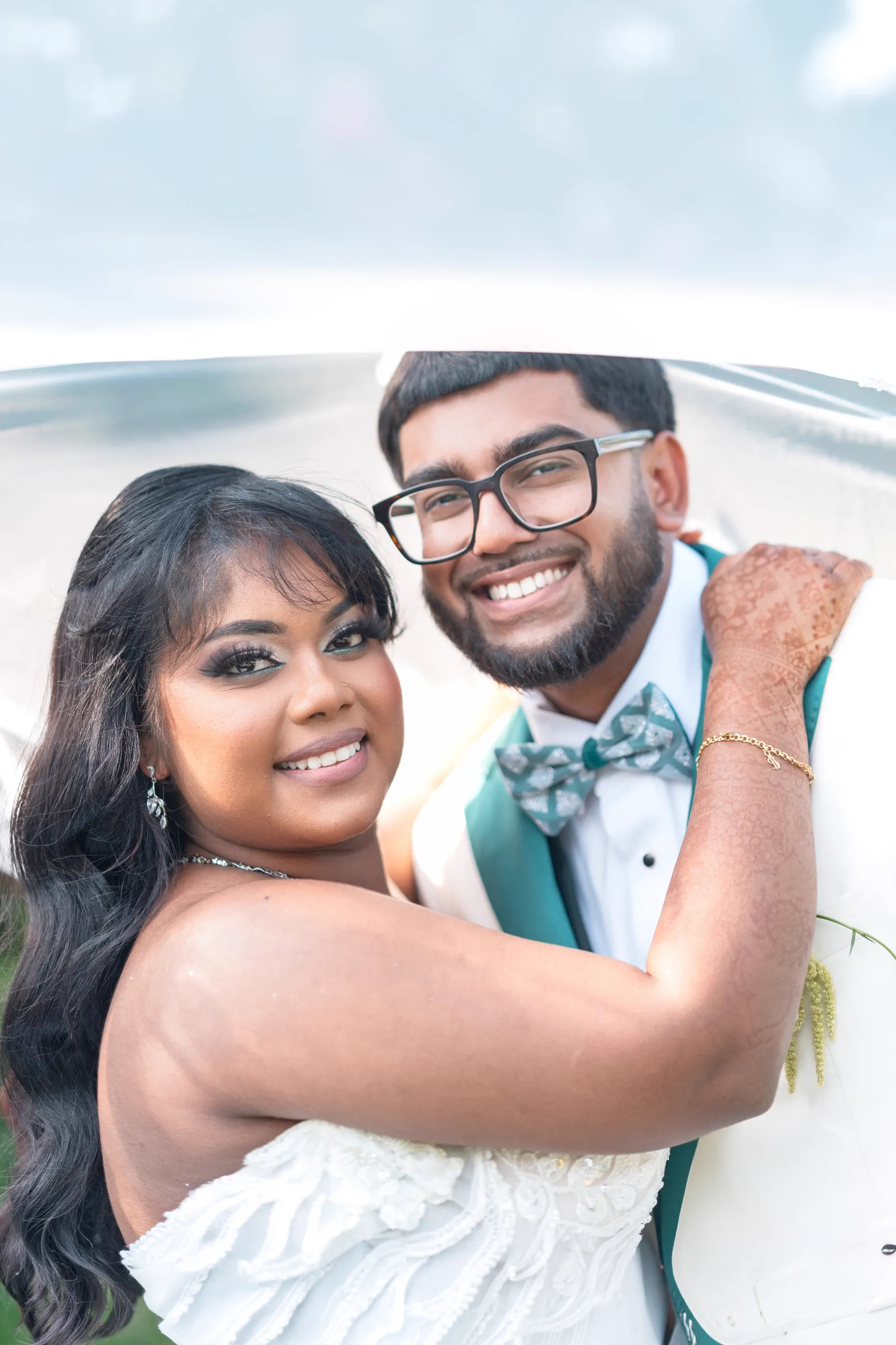 A newlywed couple smile together beneath the bride's veil.